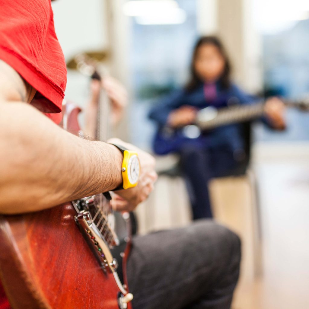 persona profesora de guitarra con estudiantes